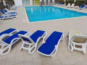 un grupo de tumbonas azules y blancas junto a una piscina en Maison 4-6 personnes, en Saint-Brevin-les-Pins