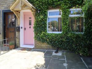a pink door on a house with ivy at Emily Cottage in Keighley