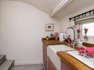 a kitchen with white walls and wooden counters and a sink at Emily Cottage in Keighley +15 photos