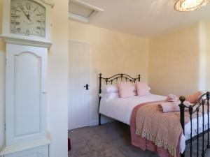 a bedroom with a bed and a clock on the wall at Emily Cottage in Keighley