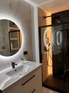 a bathroom with a sink and a shower with a mirror at Apartament City Rent Płock in Płock