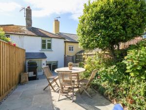 a patio with a table and chairs in front of a house at Holly Cottage in Lyme Regis