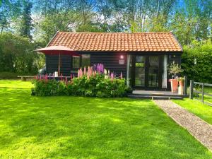 a small cabin in a yard with green grass at The Little Barn in Hoxne