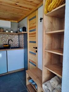 a kitchen with wooden shelves and a sink at Panoráma Kisház in Tarján