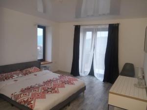 a bedroom with a bed and a large window at Casa Prieteniei - rezervare integrală in Bistriţa