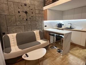a living room with a couch and a clock on the wall at Studio Lazur in Burgas