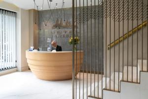 Un hombre sentado en un mostrador de recepción en un vestíbulo. en Hotel Universal, en Santiago de Compostela