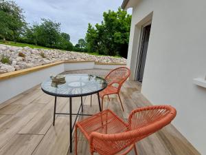 a patio with a glass table and two chairs at La Reinette des Prés in Doudeauville