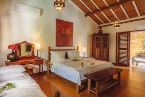 a bedroom with a bed and a table and a mirror at Pousada Encantada in Trancoso +40 photos