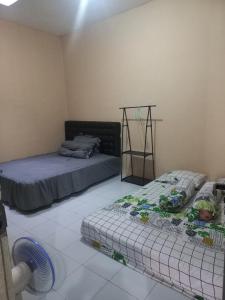 a bedroom with two beds and a fan at Esvania Homestay2 in Seturan