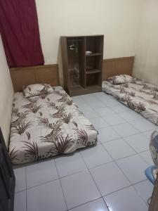 two beds in a room with a tiled floor at Esvania Homestay2 in Seturan