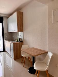 eine kleine Küche mit einem Holztisch und weißen Stühlen in der Unterkunft Villa Millene in Neum