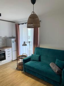ein Wohnzimmer mit einer grünen Couch und einer Küche in der Unterkunft Przytulna kawalerka nad Jeziorem Długim darmowy parking i rowery in Olsztyn