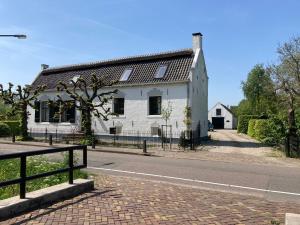 a white house on the side of a road at Beautiful renovated Farmhouse in Ankeveen