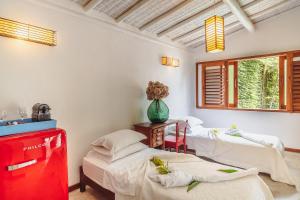 a room with three beds and a vase on a table at Pousada Encantada in Trancoso