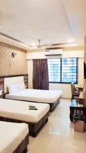 a hotel room with three beds and a chair at Hotel Golden Park Near NESCO in Mumbai