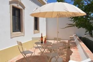 ein Tisch und Stühle unter einem Sonnenschirm auf einer Terrasse in der Unterkunft Quinta do Coelhoazul in Quelfes