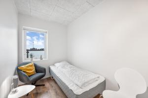 a room with a bed and a chair and a window at Lovely Holiday Apartment With A Large Balcony Facing The Dunes - 1020 in Ringkøbing