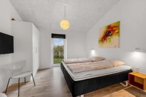 a bedroom with a bed and a table and a chair at Luxurious 8-Person House With A Spacious Outdoor Spa - 1003 in Ringkøbing