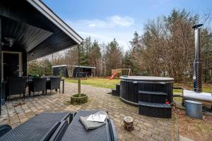 a patio with a table and chairs and a playground at Lovely 6-Person Cottage With Outdoor Sauna - 1007 in Ringkøbing