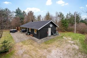 a black cabin in the middle of a yard at Lovely 6-Person Cottage With Outdoor Sauna - 1007 in Ringkøbing