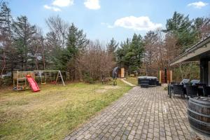 a backyard with a playground and a play set at Lovely 6-Person Cottage With Outdoor Sauna - 1007 in Ringkøbing +5 photos