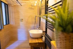 a bathroom with a white sink on a wooden table at Le Mas de la Pouzolle - Chambre en cave voutée avec petit déjeuner in Le Garn