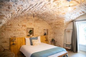 a bed in a room with a stone wall at Le Mas de la Pouzolle - Chambre en cave voutée avec petit déjeuner in Le Garn +9 photos