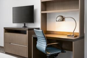 a room with a desk with a television and a chair at Hyatt House Naples 5th Avenue in Naples