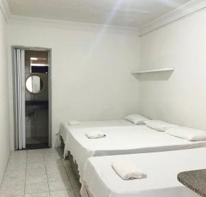 two beds in a white room with a mirror at Pousada Brisa do Mar in Aracaju