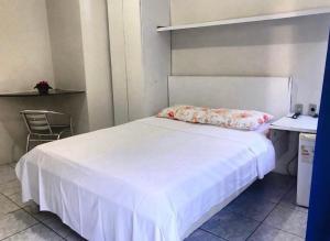a bedroom with a white bed and a chair at Pousada Brisa do Mar in Aracaju