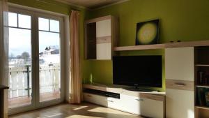 a living room with a television and a balcony at Ferienwohnung Sonnenblume in Halblech