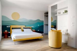 a bedroom with a bed and a yellow chair at InLoco - Natural Experience in Acqualagna
