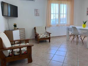 Una sala de estar con sillas, una mesa y un televisor. en Casa Lana, en Cabras