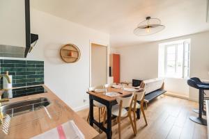 una cucina e un soggiorno con tavolo e lavandino di Evasion Paimpol appartement neuf et confortable a Paimpol