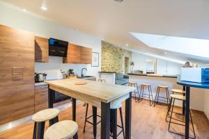 a kitchen with a wooden table and some bar stools at Grande maison familiale avec jardin parking et jeux in Saint-Carreuc