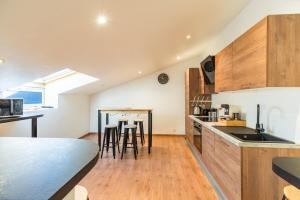 a kitchen with wooden cabinets and a table with stools at Grande maison familiale avec jardin parking et jeux in Saint-Carreuc +37 photos