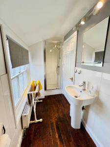 a white bathroom with a sink and a shower at Characterful & cosy cottage with large double room in Manningtree