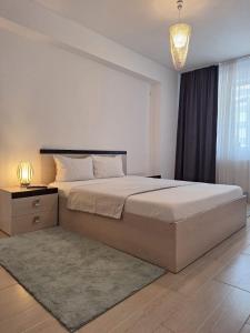 a bedroom with a large bed and a chandelier at Cazare Apartament 2 camere in Chiajna