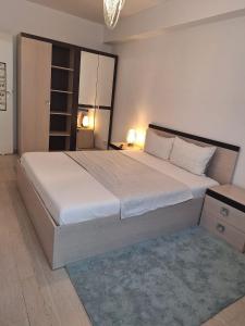 a bedroom with a large white bed with a blue rug at Cazare Apartament 2 camere in Chiajna
