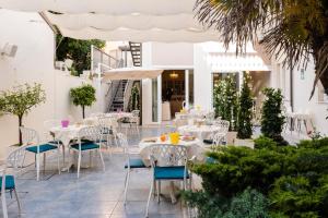 a restaurant with white tables and chairs and palm trees at Hotel London in Viareggio