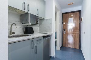 a kitchen with white cabinets and a sink and a door at Paradise Playa del Cura in Las Palmas de Gran Canaria
