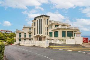ein großes Gebäude mit einem weißen Zaun vor einer Straße in der Unterkunft Guethary sur la plage in Guéthary