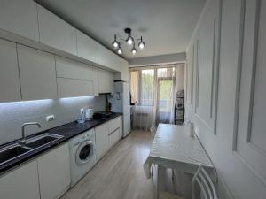 a kitchen with white cabinets and a sink and a dishwasher at ЖК Фрунзе in Bishkek