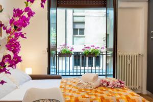 a bedroom with a bed and a balcony with flowers at APARTMENTS VISTALLIHOUSE in Bergamo