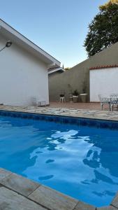 a swimming pool with blue water in front of a house at Casa em Águas de Lindóia in Águas de Lindóia