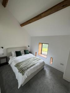 a bedroom with a large white bed with a window at Threshing Barn- Modern 5 Bed, 10 person, Barn Conversion in a Rural Location with Great Access in Silkstone