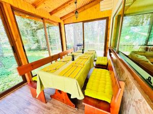a dining room with a table and benches and windows at Вила Данели in Tsigov Chark