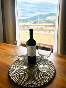 a bottle of wine and two wine glasses on a table at Piso Playa de Los Barcos in Isla