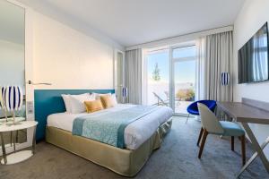 een hotelkamer met een bed en een bureau en een tafel en stoelen bij Golden Tulip Marseille Euromed in Marseille